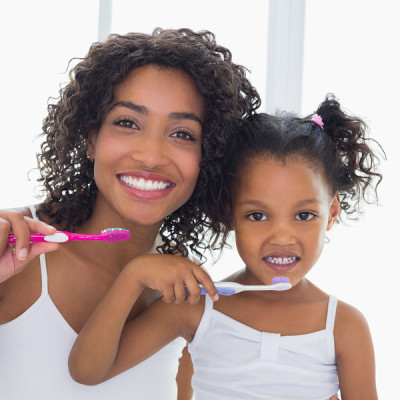 Pretty mother with her daughter brushing their teeth at home in